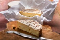 Французский мягкий сыр на деревянной доске с ножом и в упаковке — стоковое фото