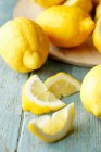 Vários limões inteiros e fatias de limão em um fundo turquesa — Fotografia de Stock