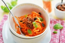 Carrot spaghetti with dried tomato pesto, pumpkin seeds and fresh basil — Stock Photo