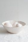 Біла керамічна миска з білими яйцями — стокове фото