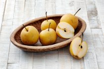 Nashi pears in wooden bowl on rustic wooden surface — Stock Photo