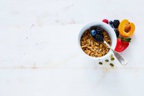 Weiße Frühstücksschale mit leckerem hausgemachtem Müsli, frischen Beeren und Früchten auf rustikalem Hintergrund — Stockfoto