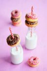 Mini doughnuts with icing and sugar strands, and vegan milk in bottles — Stock Photo