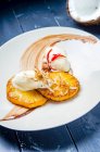 Honig glasierte gegrillte Ananas mit Kokossorbet-Eis, Kokosraspeln und Chili auf weißem Teller und blauem Tisch — Stockfoto