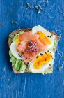 Panino aperto con avocado, uova, salmone, germogli e semi di sesamo — Foto stock