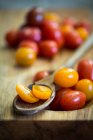 Tomates cherry en una tabla de madera y una cuchara de madera - foto de stock