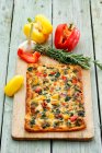 A pizza topped with peppers, garlic and rosemary - foto de stock