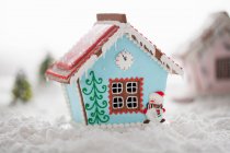 Casa de jengibre con glaseado azul y muñeco de nieve comestible - foto de stock