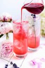 Gin tonic with blackberry syrup dripping from jug — Stock Photo