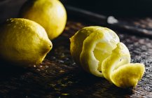 Fresh lemons, partly peeled on rustic wooden surface — Stock Photo