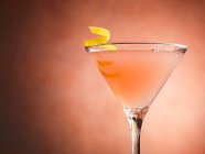 Космополітанський коктейль з закрученою лимонною цедрою в склянці — стокове фото