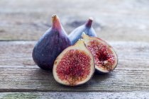Fresh figs, whole and halved, on wooden table — Stock Photo