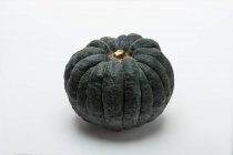 A dark green pumpkin on a white surface — Stock Photo