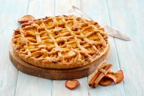 Яблочный пирог с решеткой сверху и звездами выпечки на деревянной тарелке — стоковое фото