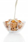Milk being pouring on cornflakes in glass bowl — Stock Photo