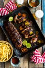 Pork ribs on baking sheet with limes — Stock Photo