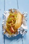 Hot dog con cetriolo e cipolle in foglio di alluminio — Foto stock