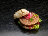 Close-up shot of delicious hamburger with red onions and lettuce — Stock Photo