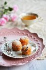 Piccoli muffin su un piatto con una forchetta, una tazza da tè e fiori — Foto stock