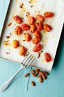 Date tomatoes sprinkled with salt and filled with almonds, on a baking sheet — Stock Photo