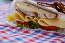 Un sandwich composé de pain croûté, fromage, tomates et salade — Photo de stock