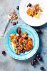 Pêches grillées, abricots, prunes, servis avec yaourt grec et pistaches dans des assiettes — Photo de stock