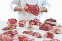 Шеф-повар представляет различные виды свежего сырого мяса — стоковое фото