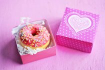 Mini donuts com cobertura e polvilhas de açúcar em uma caixa de presente — Fotografia de Stock