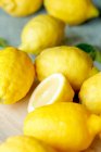 Plusieurs citrons entiers et coupés en deux (gros plan) — Photo de stock