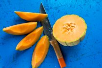 Un demi melon cantaloup et des quartiers de melon avec un couteau — Photo de stock