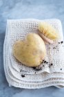 Une pomme de terre en forme de coeur et une brosse sur un torchon — Photo de stock