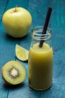 A kiwi and apple smoothie with lime in a bottle with a straw — Stock Photo