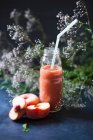 Арбуз и персиковый смузи в стеклянной бутылке с соломинкой — стоковое фото