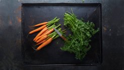 Морковь с отрезанными листьями на подносе для выпечки — стоковое фото