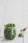 Green kale pesto in a jar and on a spoon — Stock Photo