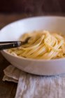 Cooked Tagliatelle with butter and fork in bowl — Stock Photo