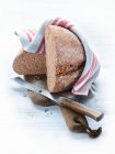 Wholemeal wheat bread on a chopping board with a knife and a tea towel — Stock Photo