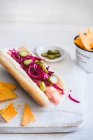A hot dog with pickled red cabbage and gherkins — Stock Photo