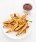 Картофельные клинья с паприкой, посыпанные морской солью и луком, томатный соус сбоку — стоковое фото