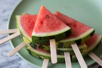 Wedges of watermelon with lollipop sticks on plate — Stock Photo