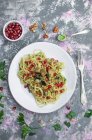 Spaghetti with parsley walnut pesto, eggplant and pomegranate - foto de stock