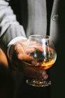 A man holding a glass of bourbon — Stock Photo