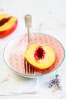 Half a peach in a bowl with a fork — Stock Photo