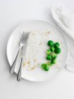 Brussels sprouts on plate with leftovers — Stock Photo