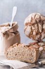 Pane fatto in casa su un panno accanto a un sacchetto di farina e un coltello — Foto stock