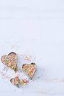 Conjunto de três cortadores de biscoito coração preenchido com colorido polvilhado na superfície branca — Fotografia de Stock