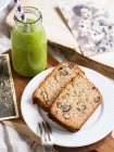 Two slices of flourless (almond and coconut flour) banana bread with nuts, served with green smoothie — Stock Photo