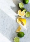 Limões e limas, inteiros, cortados pela metade e fatias — Fotografia de Stock