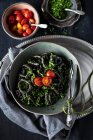 Nudeln mit Spinat, Tomaten und Basilikum auf dunklem Hintergrund. Selektiver Fokus. — Stockfoto