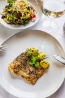 Fried fish in a poppy seed crust with potatoes and mixed salad — Stock Photo
